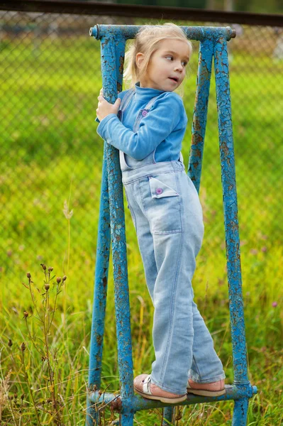 Little girl on rusty blue gymnastic apparatus — Stock Photo, Image