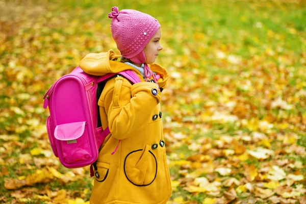 Ragazza in cappotto giallo e zaino rosa va a scuola — Foto Stock