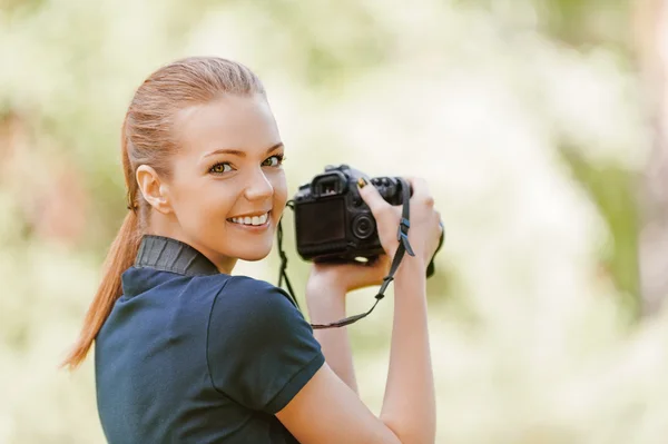 Улыбающаяся молодая женщина с камерой — стоковое фото