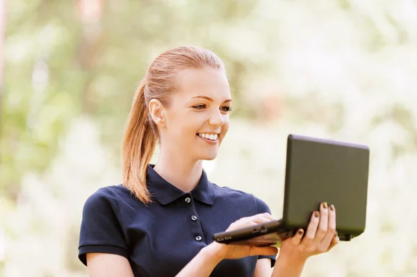 Dizüstü bilgisayarda çalışan genç kadın gülümsüyor — Stok fotoğraf