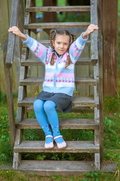 Kleines Mädchen sitzt auf Holztreppe — Stockfoto