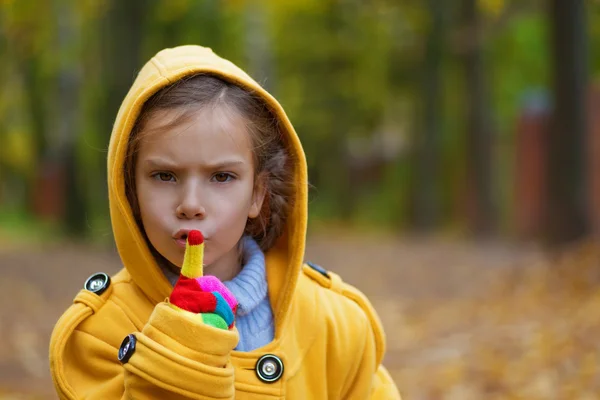 Küçük kız sarı montlu parmak dudaklar için koymak. — Stok fotoğraf