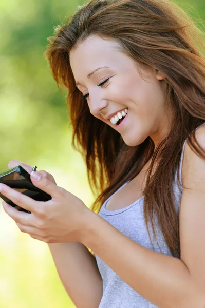 Sorrindo jovem mulher escrevendo no dispositivo — Fotografia de Stock