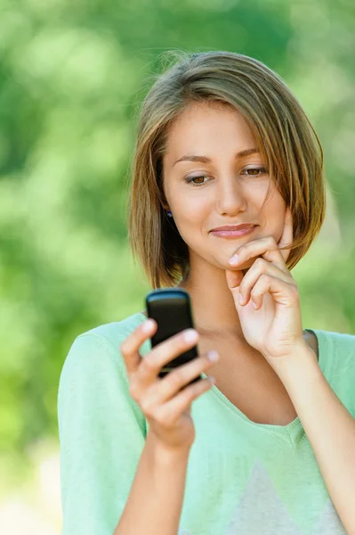 Young woman reads sms on mobile phone — Stock Photo, Image