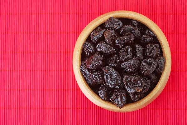 Dried prunes in wooden bowl — Stock Photo, Image