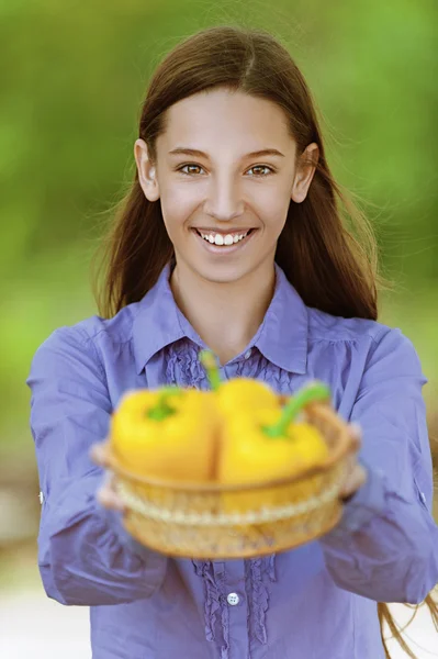 Glimlachend tiener meisje met mand van gele paprika — Stockfoto