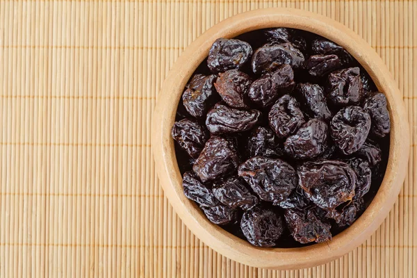 Dried prunes in wooden bowl — Stock Photo, Image