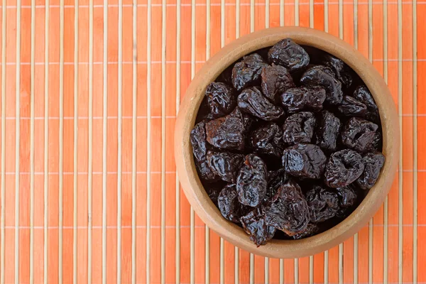 Dried prunes in wooden bowl