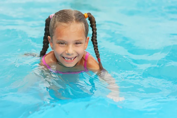 Smiling little girl swims in pool — Stock Photo, Image