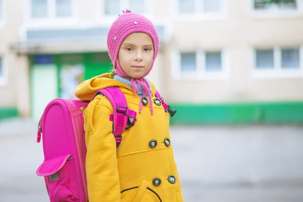 小さな女の子が黄色いコートとピンクのナップザック — ストック写真