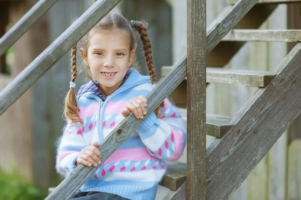 Mosolygó lány ül a fa lépcsők a bolzákon — Stock Fotó