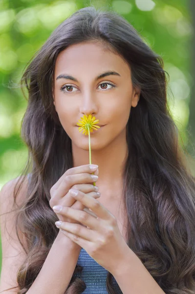Jovem mulher cheirando flor amarela — Fotografia de Stock