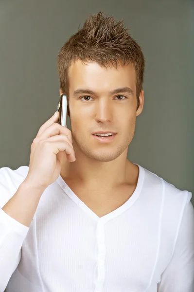 Jovem homem de camisa branca falando no celular — Fotografia de Stock