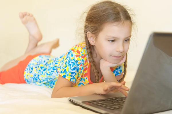 Fröhliches Mädchen liegt und schaut auf Laptop — Stockfoto