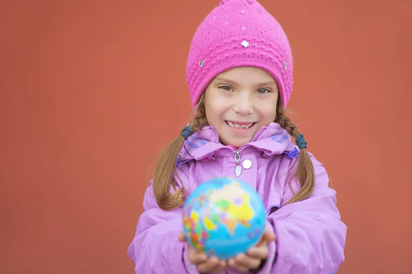 Allegra ragazza in giacca rosa tenendo globo — Foto Stock