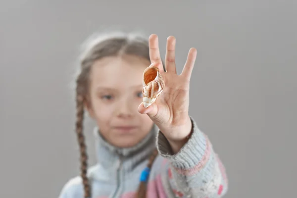 Little girl in sweater with seashell — Stock Photo, Image