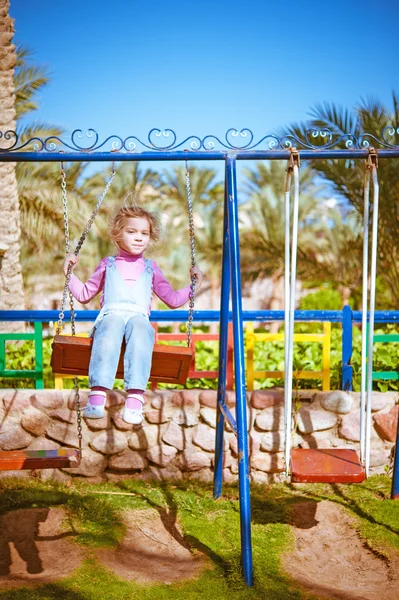 Meisje op schommel in stad kinderpark — Stockfoto