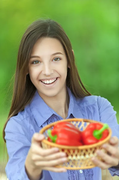 Menina adolescente sorridente com cesta de pimentas vermelhas — Fotografia de Stock