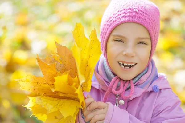 Bambina in cappotto giallo raccoglie foglie di acero giallo — Foto Stock