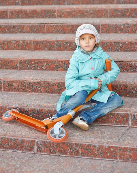 Menina com capa azul com scooter — Fotografia de Stock