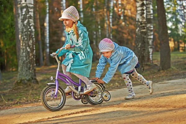 Dvě malé holčičky na koni hračka cyklus — Stock fotografie