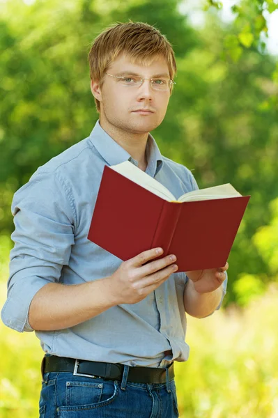 Estudante (masculino) com óculos livro de leitura — Fotografia de Stock