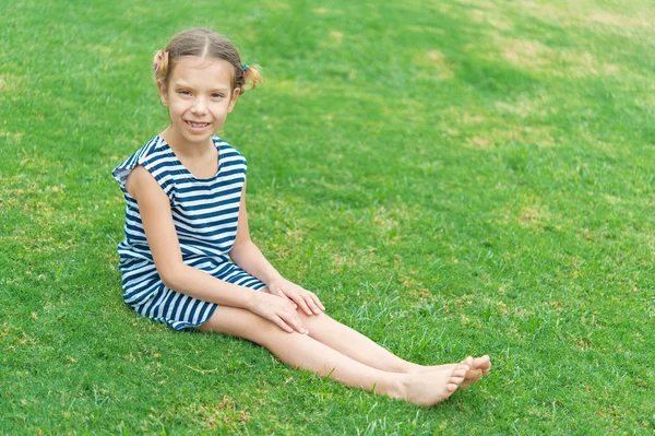 Belle fille souriante assise sur l'herbe verte — Photo