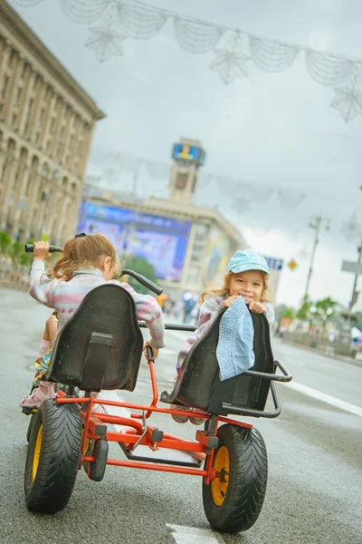 Dvě malé holčičky na koni hračka cyklus — Stock fotografie