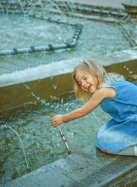 Pequeña chica hermosa jugando en la fuente — Foto de Stock