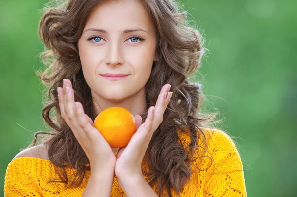 Mooie vrouw bedrijf oranje — Stockfoto