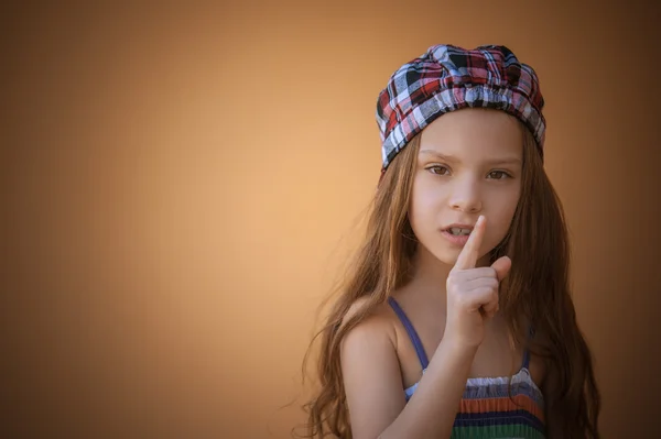 Little girl puts index finger to lips — Stock Photo, Image