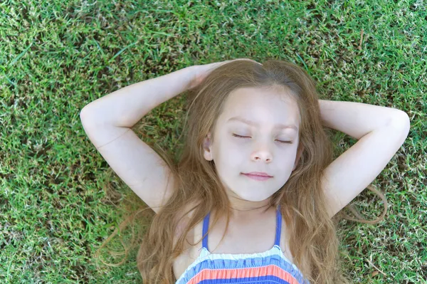 Szép, mosolygós lány fekszik, a zöld fű — Stock Fotó