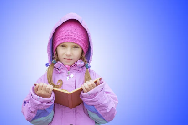 Little girl in pink coat reads book — Stock Photo, Image