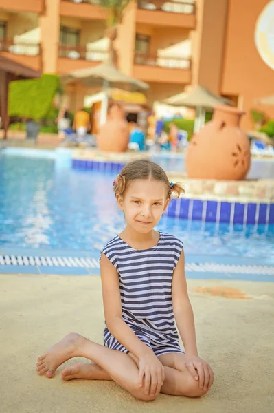 Маленькая девочка в полосатом жилете возле бассейна курорта — стоковое фото