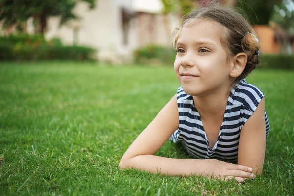 Mooi lachende meisje ligt op groen gras — Stockfoto