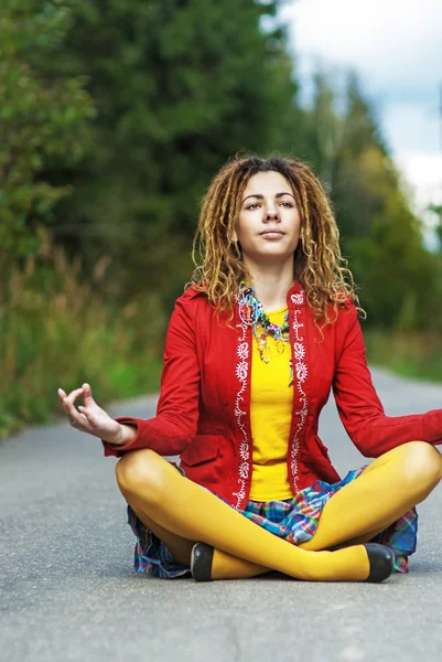 Woman with dreadlocks sitting in lotus position — Stock Photo, Image