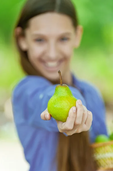 Smiling teenage girl holding basket of pears — Stock Photo, Image