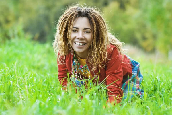 Woman with dreadlocks sitting on grass — Stock Photo, Image