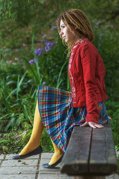 Kvinna med dreadlocks sitter på bänken — Stockfoto