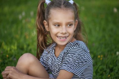 Yeşil çimenlerin üzerinde oturan güzel gülümseyen kız