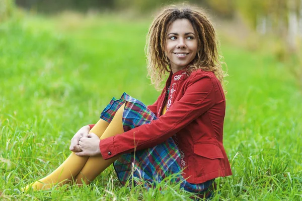 Vrouw met dreadlocks zittend op het gras — Stockfoto