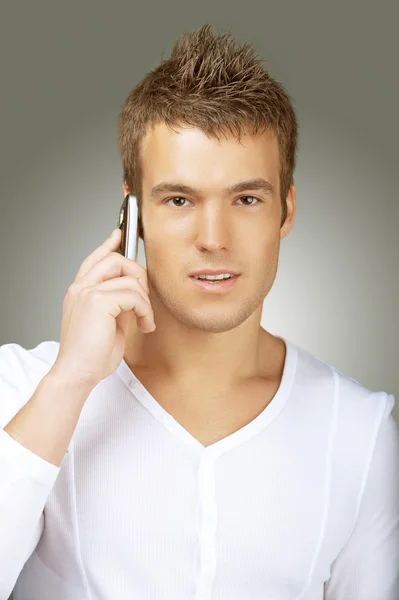 Unga mannen i vit skjorta talar i mobiltelefon — Stockfoto