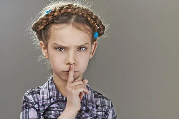 Menina coloca dedo indicador nos lábios — Fotografia de Stock