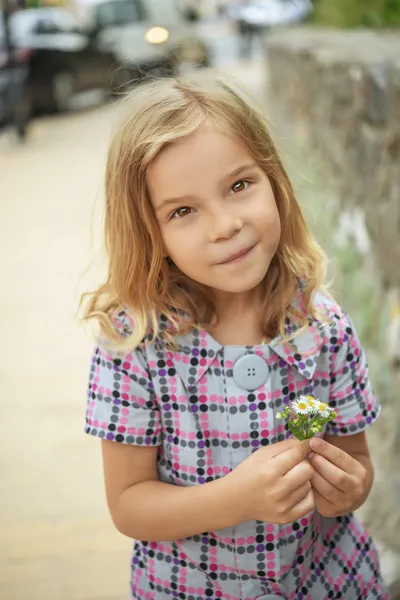 Bella ragazza sorridente che tiene il fiore — Foto Stock