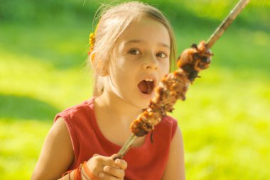 young girl eats kebab clipart