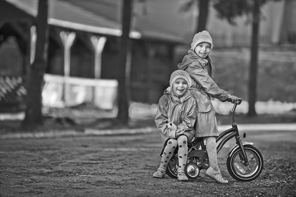 Dvě malé holčičky na koni hračka cyklus — Stock fotografie