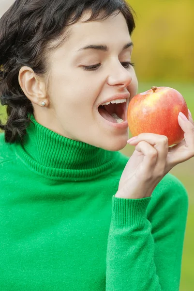 Mädchen beißt sich einen Apfel ab — Stockfoto