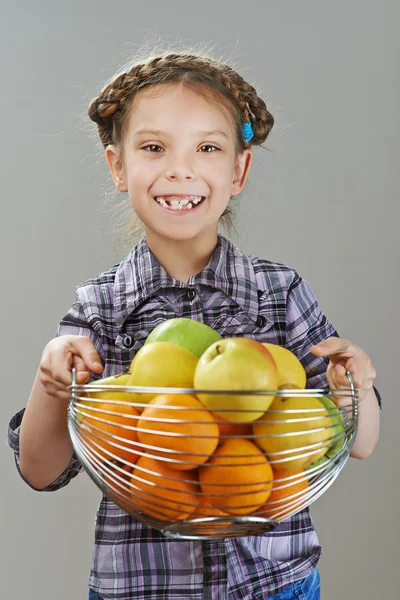 Niña sosteniendo una cesta de manzanas y naranjas —  Fotos de Stock