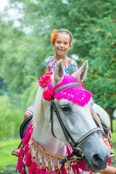 Little girl riding festive horse — Stock Photo, Image