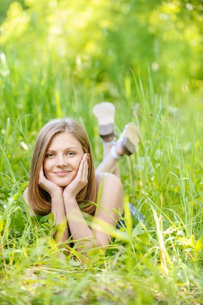 Mladá žena leží na zelené trávě — Stock fotografie